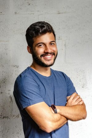 portrait photo of smiling man with his arms crossed standing in front of white wall